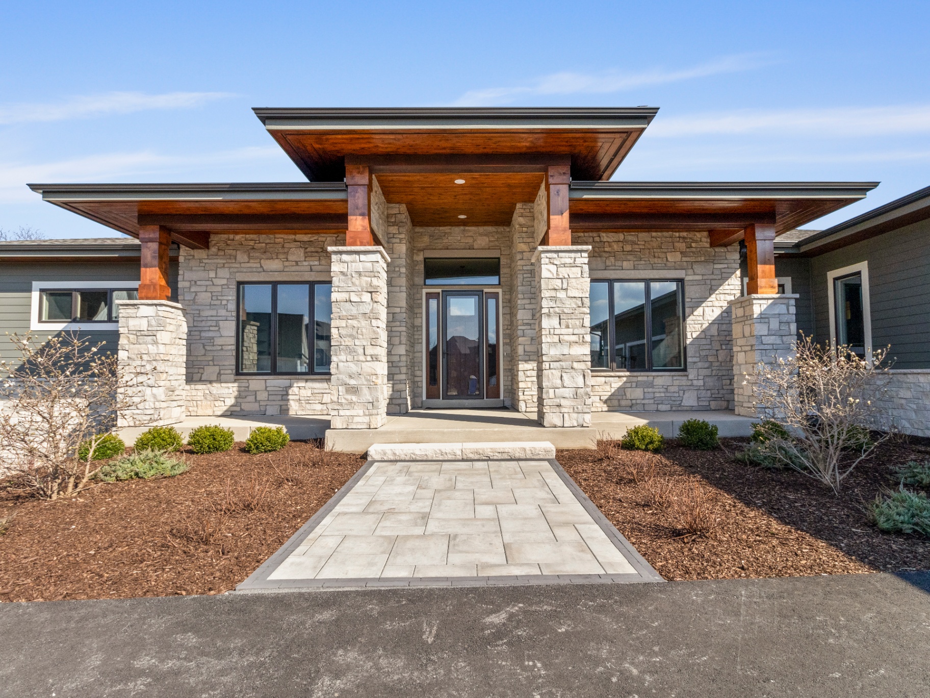 Modern prairie-style home exterior with stone facade and timber accents